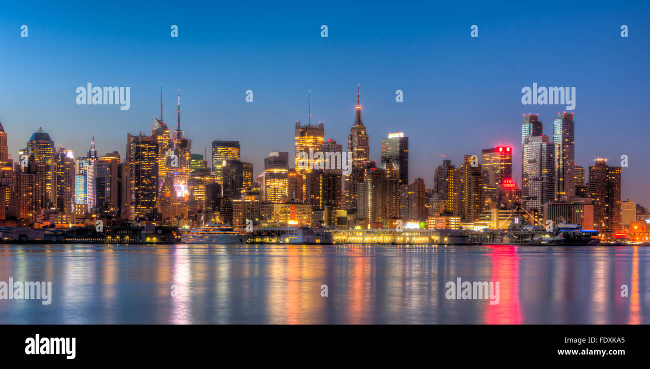 Le centre ville de Manhattan reste illuminé par des lumières qui se reflète sur la rivière Hudson avant le lever du soleil dans la ville de New York. Banque D'Images