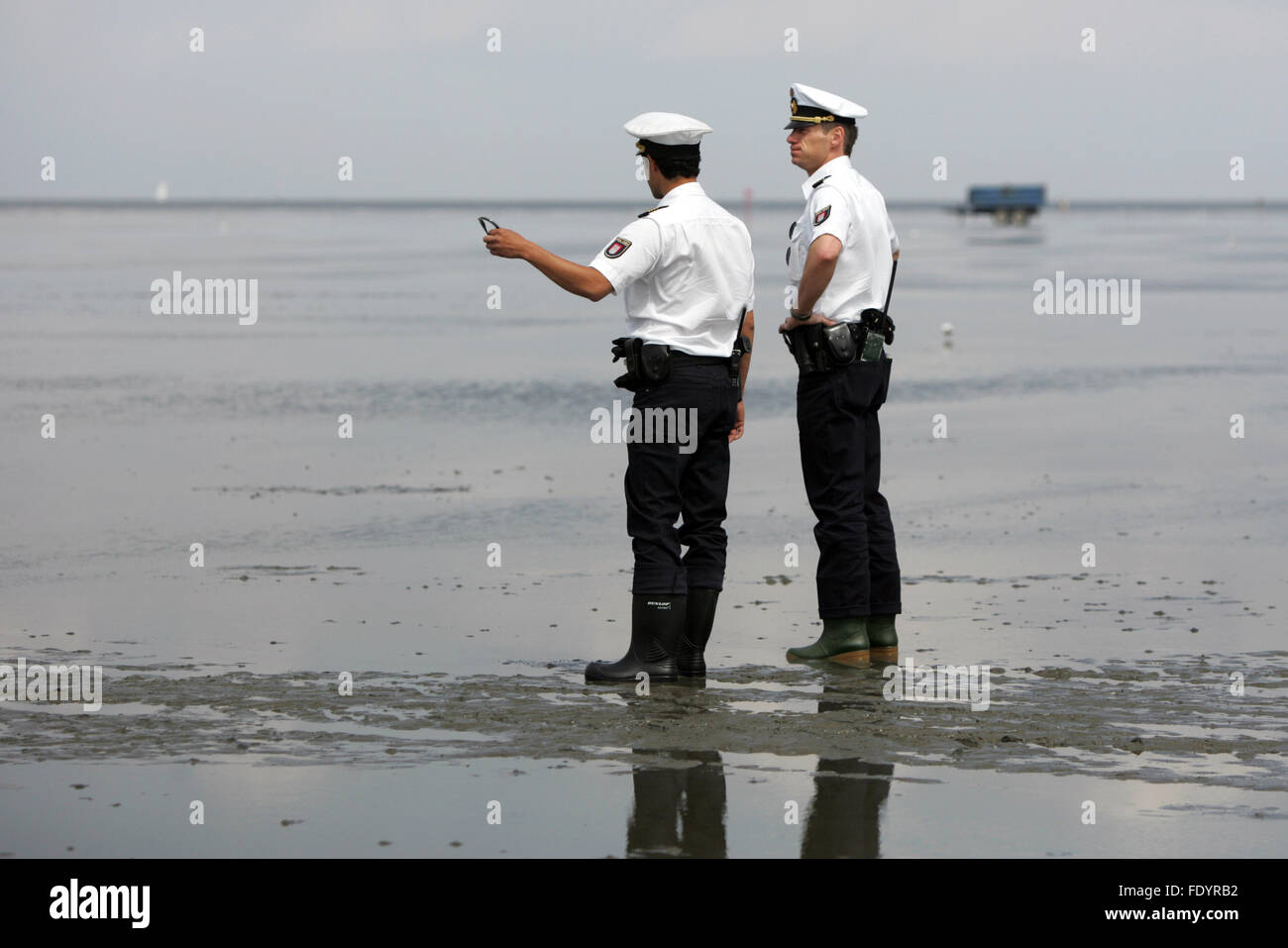 Cuxhaven, Allemagne, les officiers de police debout dans des bottes en caoutchouc dans la boue Banque D'Images