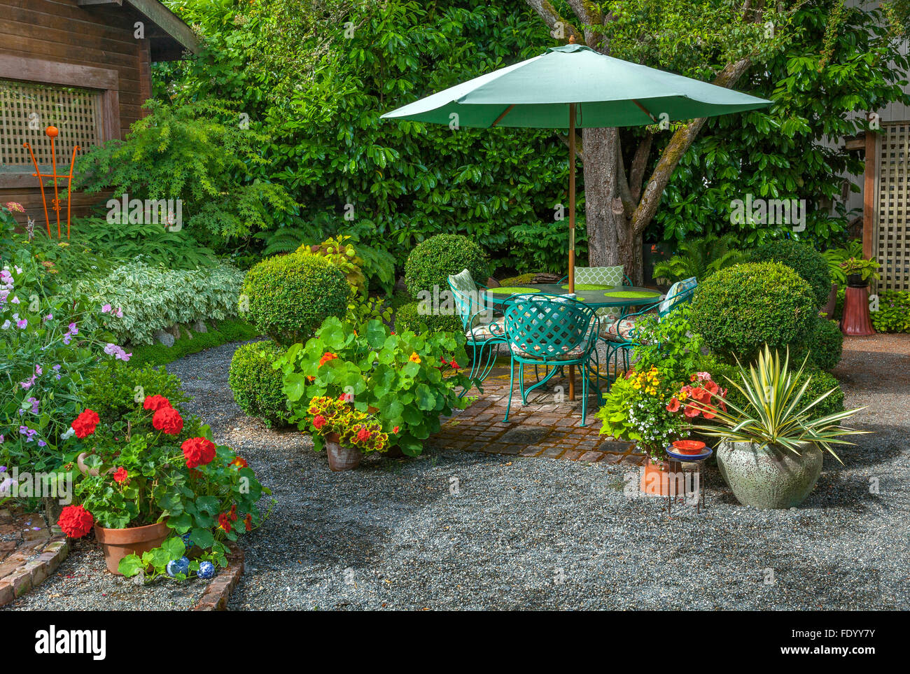 Vashon-Maury Island, WA : terrasse d'été entourée de pots de géraniums rouges, les capucines et yucca situé dans un chalet jardin Banque D'Images