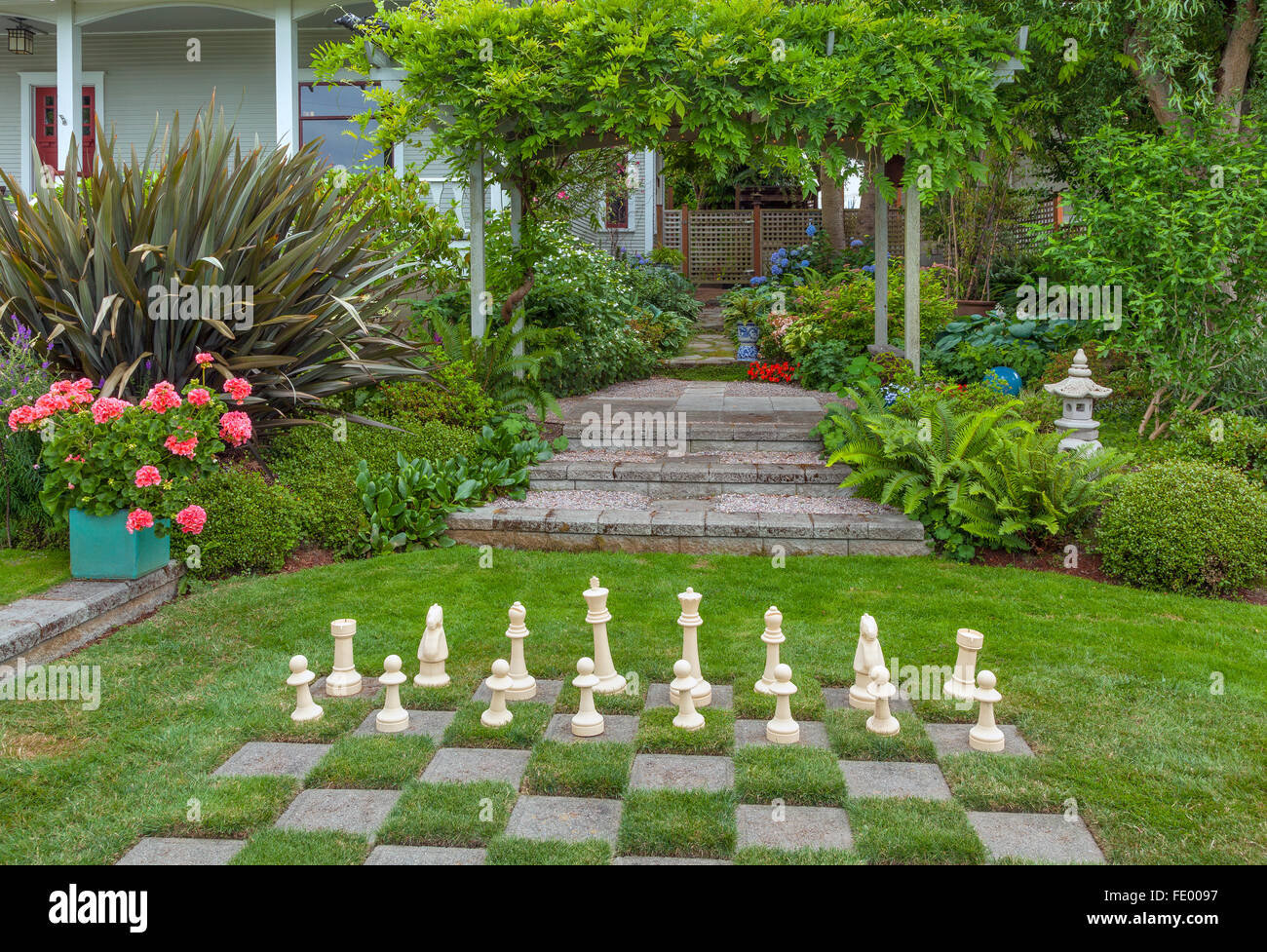 Vashon-Maury Island, WA : immense échiquier dans une pelouse dans un jardin de rose avec des géraniums, wisteria trellis, Banque D'Images