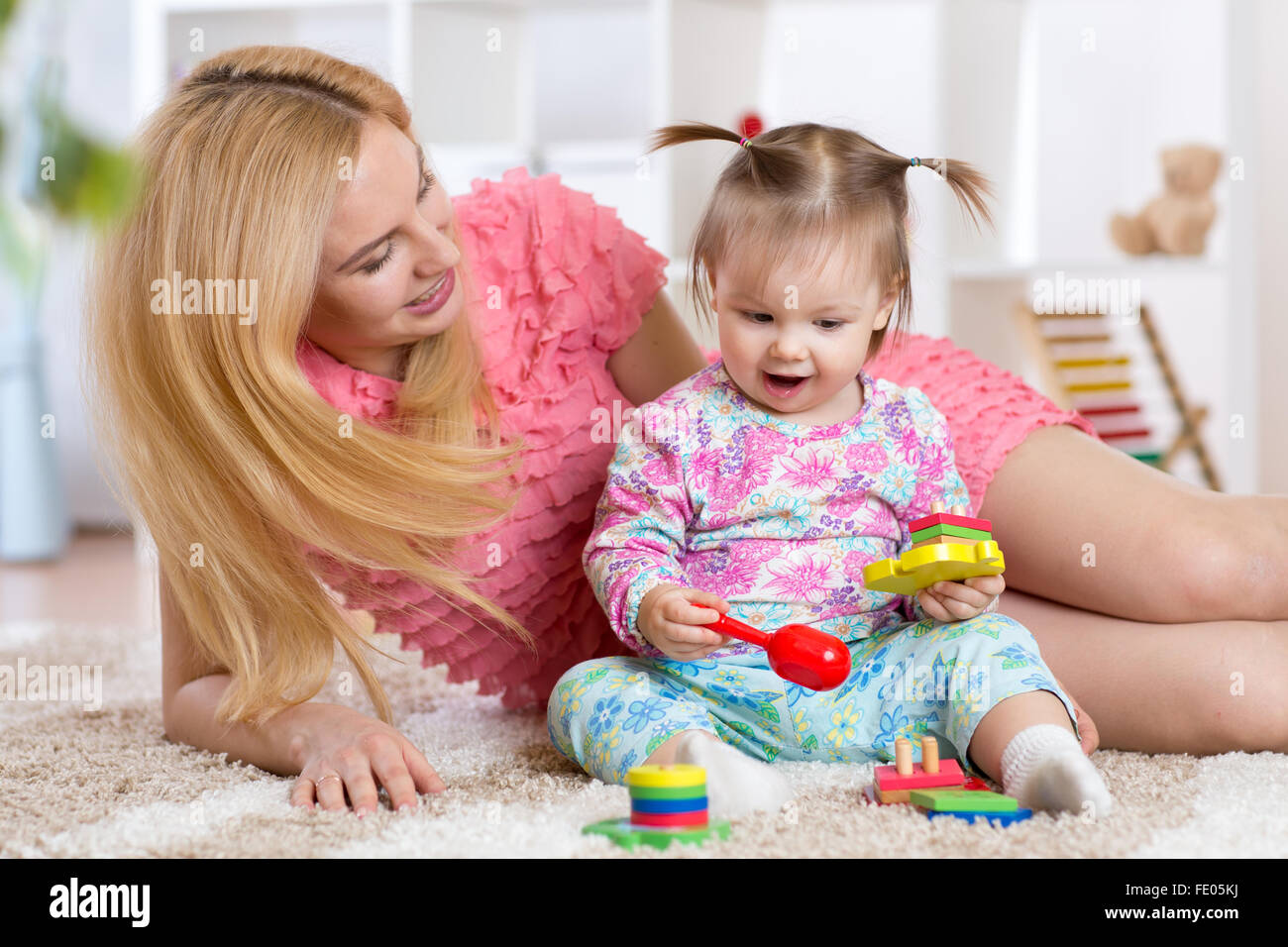 Bébé jouant avec sa mère sur un tapis en maternelle Banque D'Images