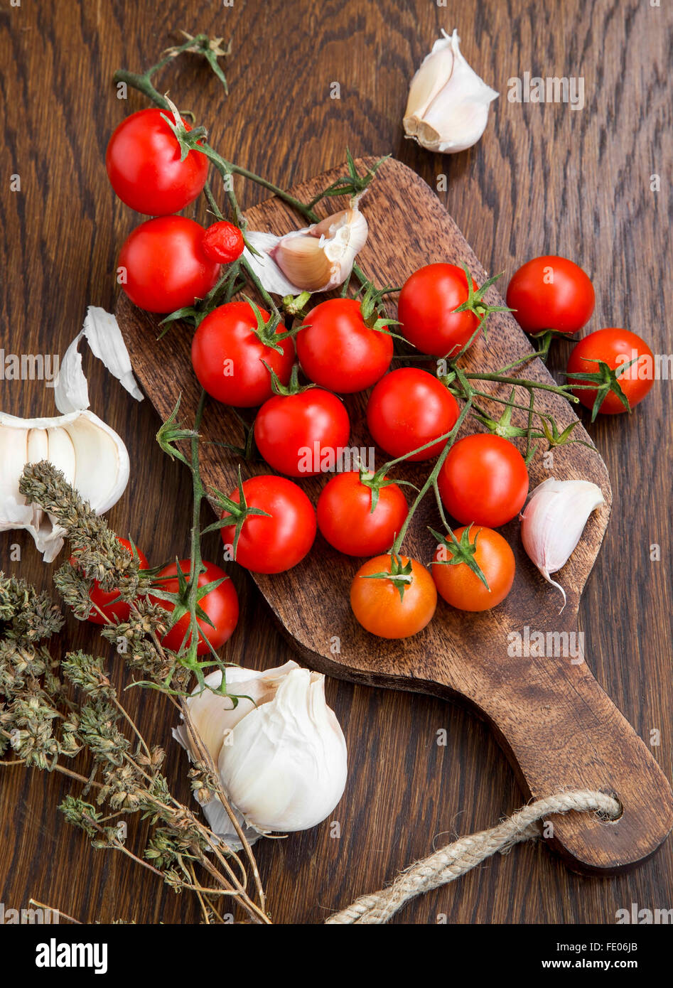 Tomates cerise bio avec de l'ail et le thym herb sur une table en bois Banque D'Images