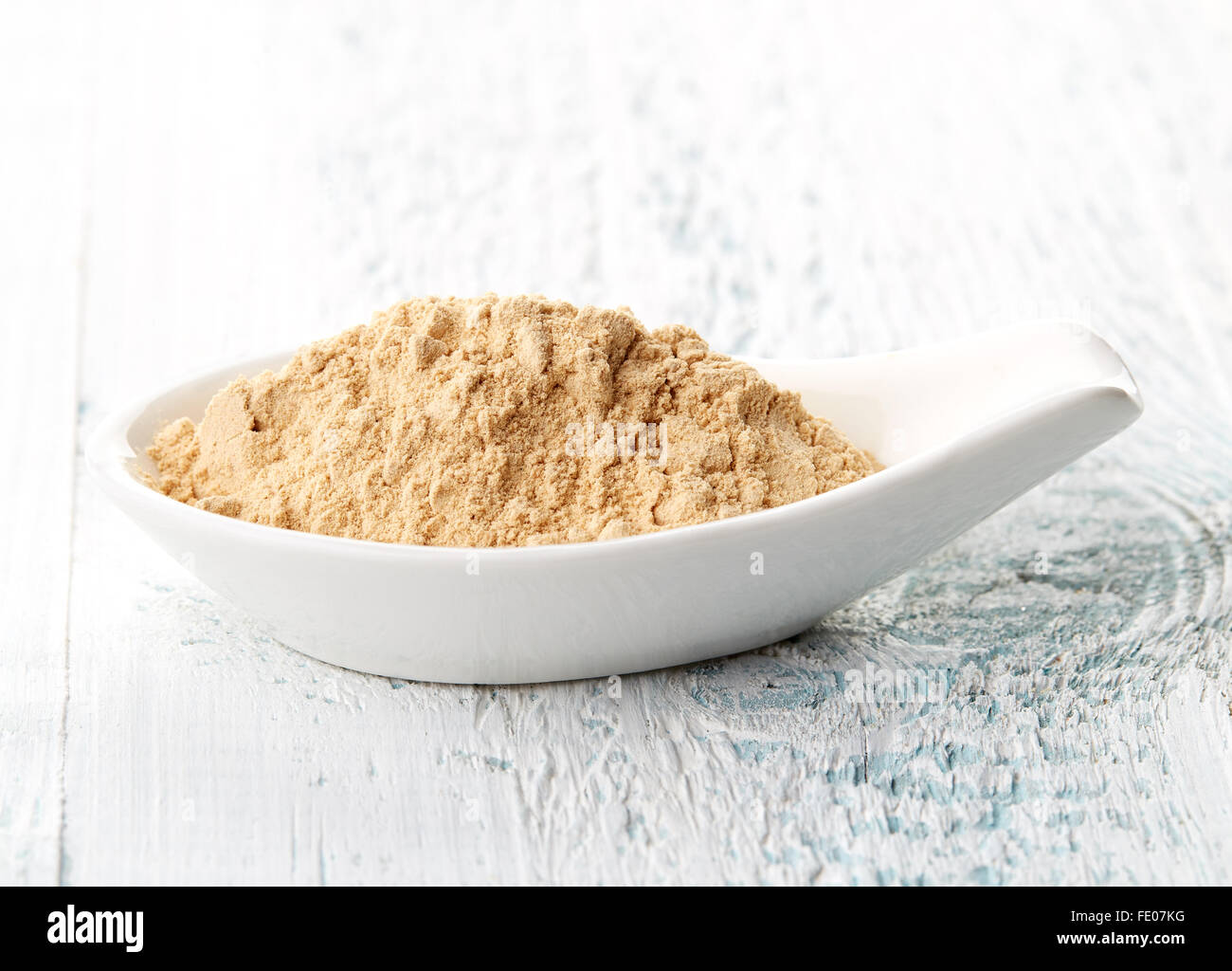 Poudre de Maca en cuillère en porcelaine blanche sur table en bois blanc Banque D'Images