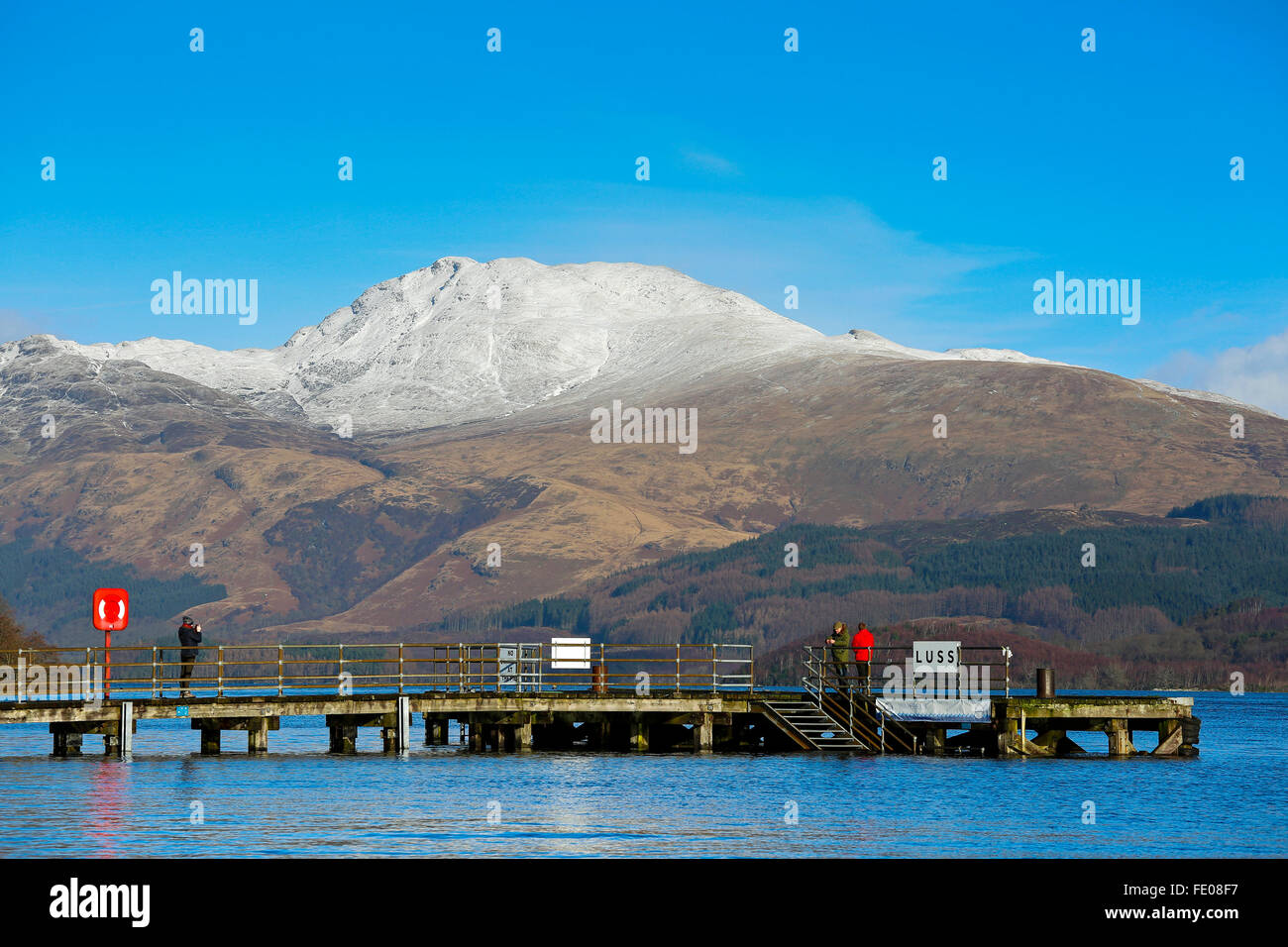 Le Loch Lomond, au Royaume-Uni. 3 Février, 2016. Après les récentes tempêtes et fortes pluies pour la saison, le niveau d'eau à Luss sur le Loch Lomond a surmonté les murs provoquant des inondations locales.Sur la première journée ensoleillée, Tom Wilson et la Géorgie à partir de Londres, en vacances près de Luss, prendre une promenade relaxante pour admirer la neige surmonté Ben Lomond et les eaux calmes du Loch Lomond. Credit : Findlay/Alamy Live News Banque D'Images
