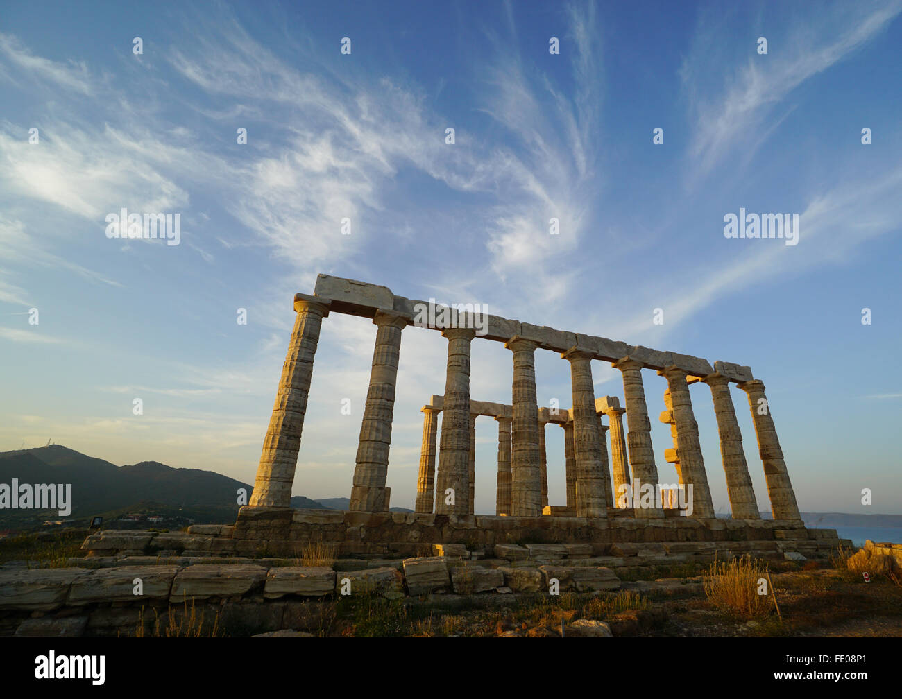 Temple de Poséidon au Cap Sounion, dans la province de l'Attique, la Grèce au cours de l'heure d'or avant le coucher du soleil sous les nuages whispy Banque D'Images