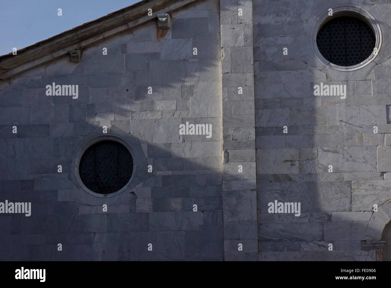 Soirée soleil projette des ombres sur un mur avec deux fenêtres circulaires. Banque D'Images