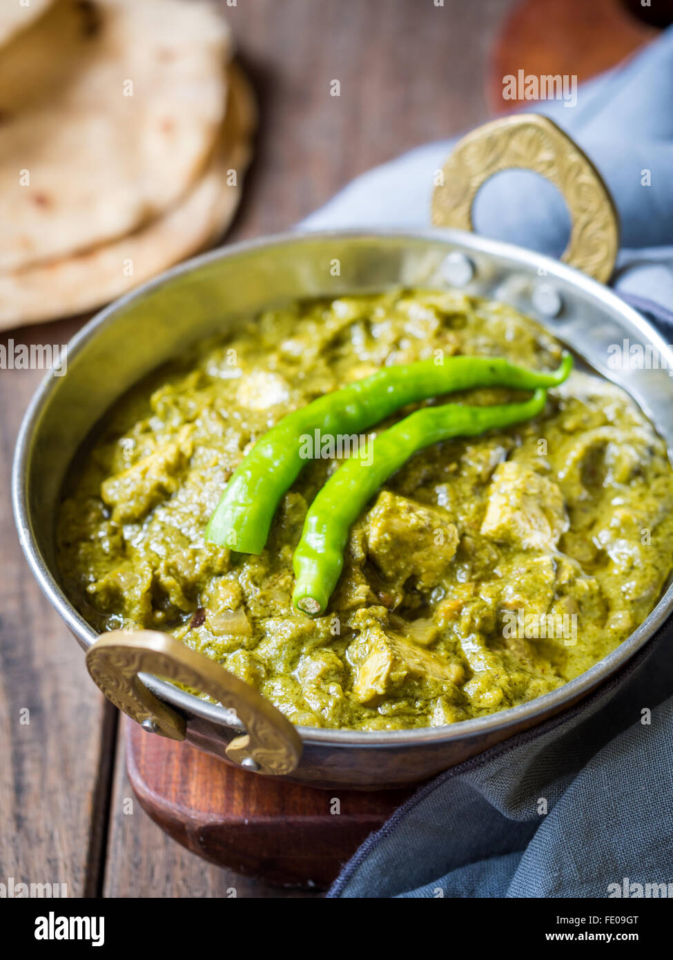 La cuisine indienne : Panir aux épinards dans un bol en cuivre traditionnel servi avec roti tandoori sur une table en bois sombre. Banque D'Images