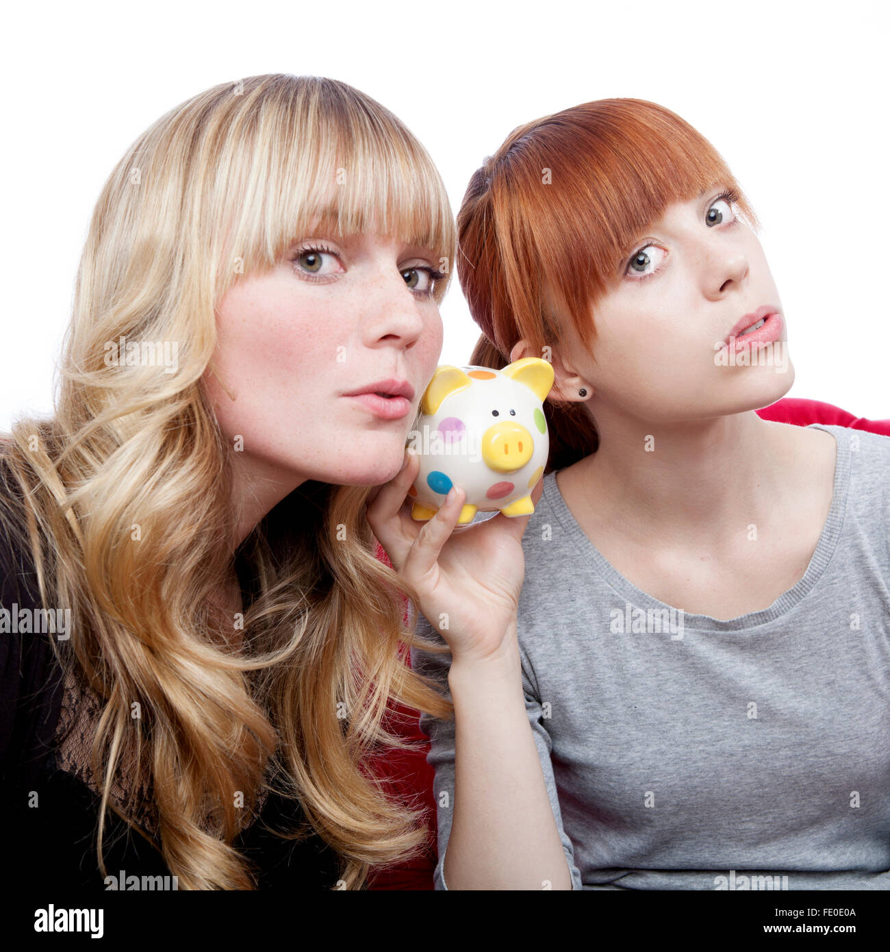 Jeune et belle blonde aux cheveux rouges pour oreilles sur moneypig sur canapé rouge in front of white background Banque D'Images