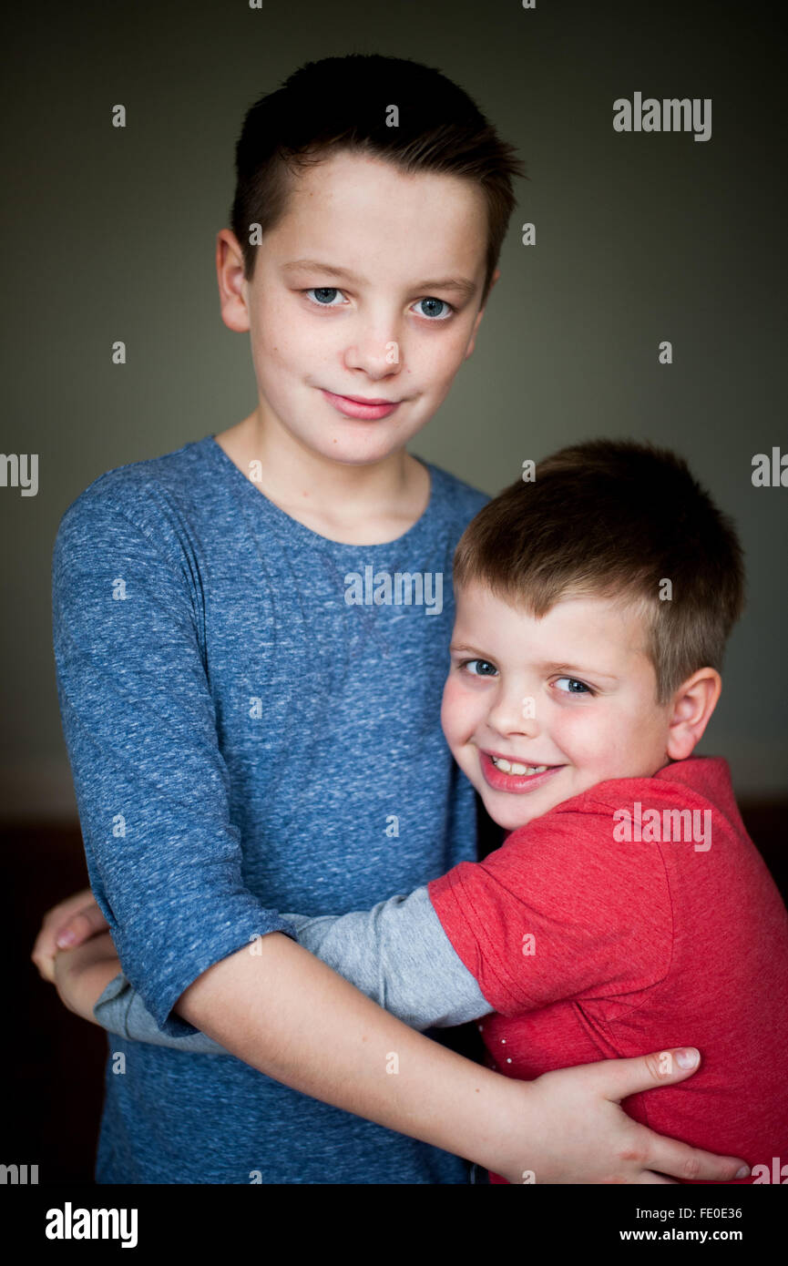 2 frères âgés de 9 et 12 ans embrassant et souriant Banque D'Images