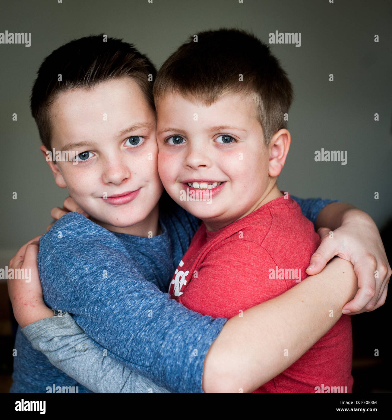 2 frères âgés de 9 et 12 ans embrassant et souriant Banque D'Images