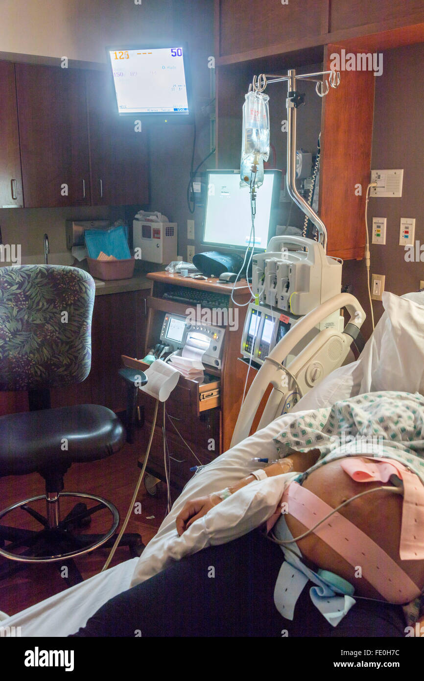 Femme enceinte au lit d'hôpital avec la surveillance de jumeaux Banque D'Images
