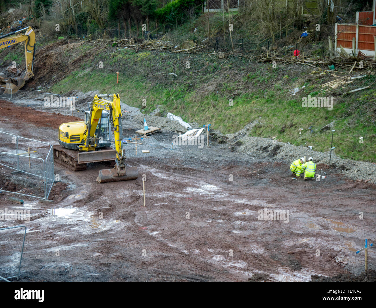 Les creuseurs travaillent avec les hommes vestes et casques de sécurité en plaçant les marqueurs en bois. Banque D'Images