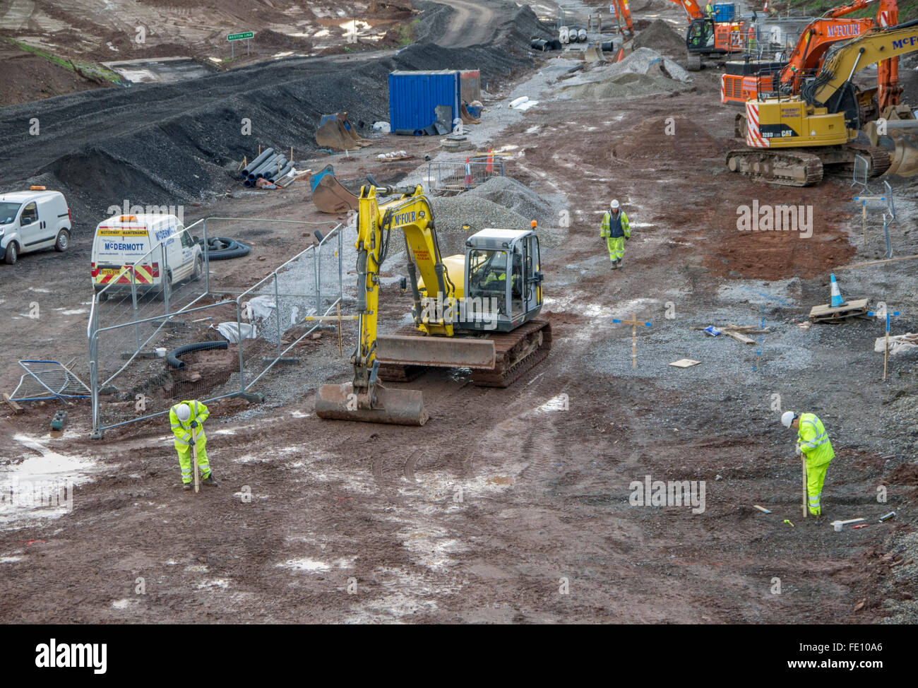 Les creuseurs travaillent avec les hommes vestes et casques de sécurité en plaçant les marqueurs en bois. Banque D'Images