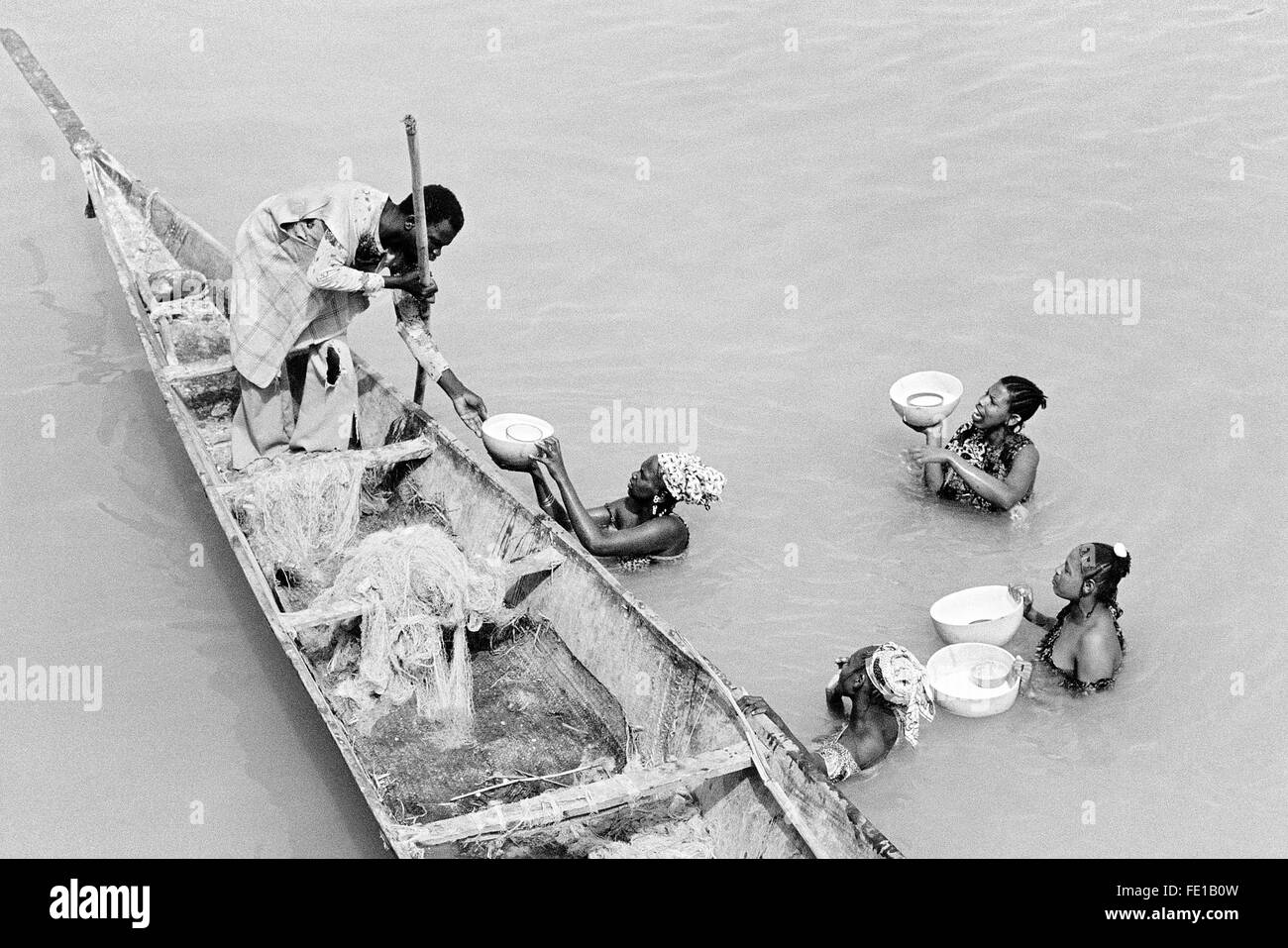 Les femmes entreprennent l'eau du fleuve Niger à la ville de Diafarabe, Mali, de vendre le lait de consommation à l'homme dans une piroque Banque D'Images