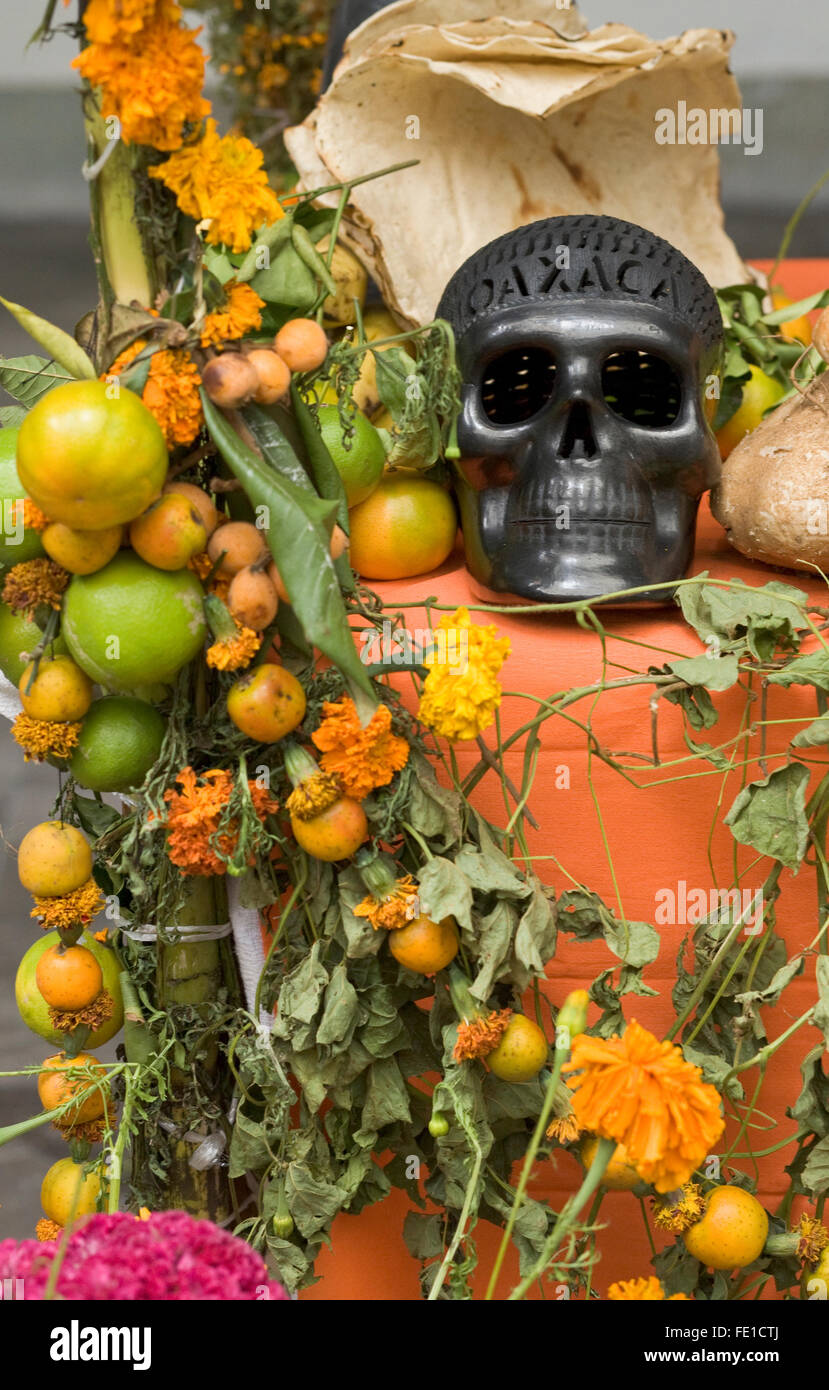 Une poterie noire, crâne avec du pain traditionnel, des fruits et des fleurs sur l'autel des offrandes pour le Jour des Morts, Oaxaca, Mexique. Banque D'Images