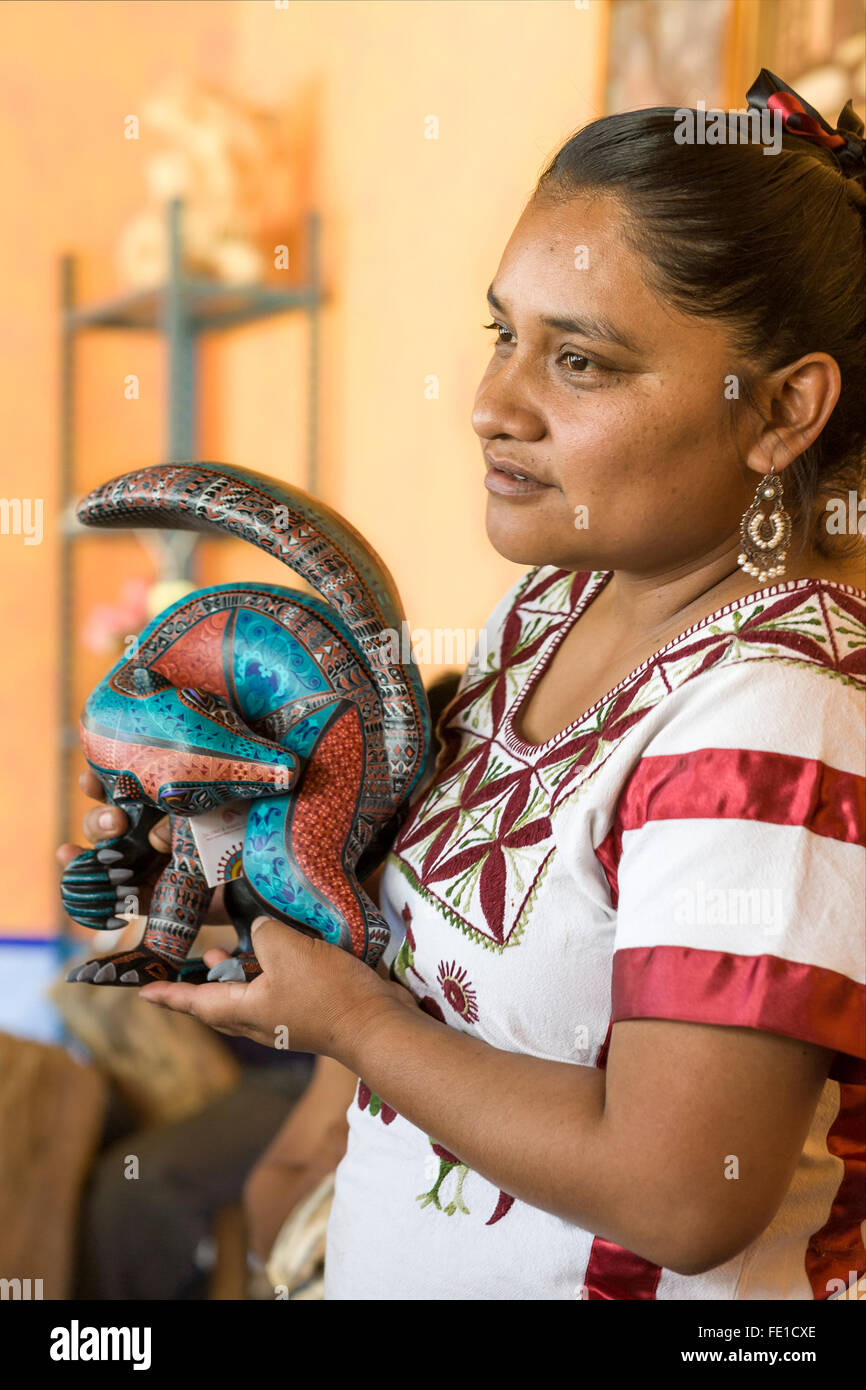 Femme zapotèque finement l'affichage de l'artisanat en bois peint à l'atelier de sculpture de Jacobo et Maria Angeles, San Martin Tilcajete, Oaxaca, Mexique Banque D'Images