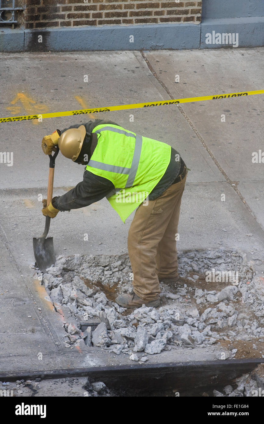 Travailleur de la construction de retirer manuellement les débris de béton cassé un trou dans le trottoir avec une pelle (FE1G87, FE1G8A, G1FE8C) Banque D'Images