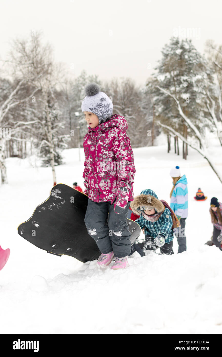 UFA - RUSSIE 16ème Janvier 2016 - Les enfants de profiter de la neige fraîche à l'aide de diapositives et de traîneaux improvisés à glisser vers le bas dans les bancs de neige Banque D'Images