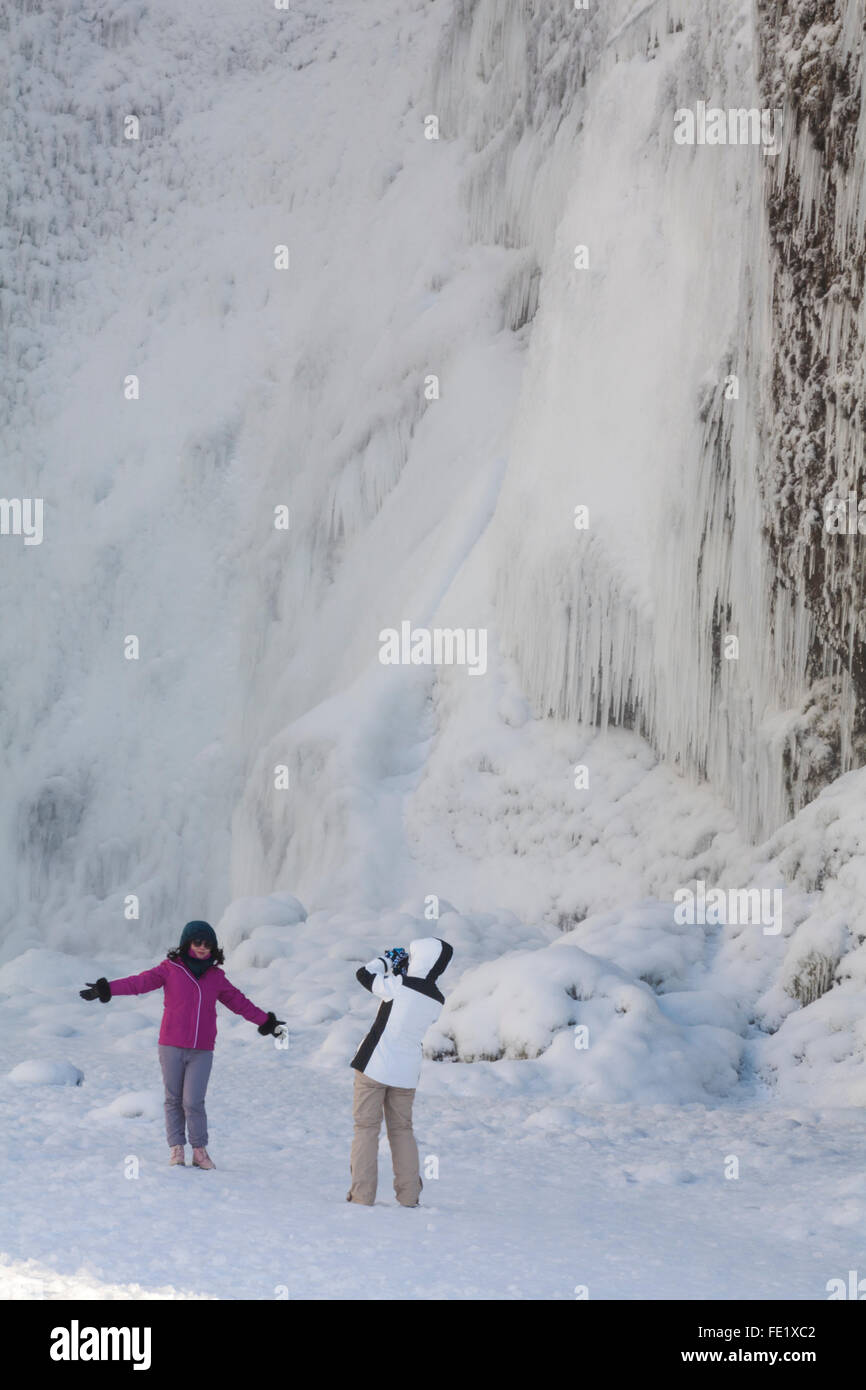 Jeune femme ayant photographie prise à Skogafoss Waterfall in winter wonderland avec l'eau gelée et de glaçons l'Islande en Janvier Banque D'Images