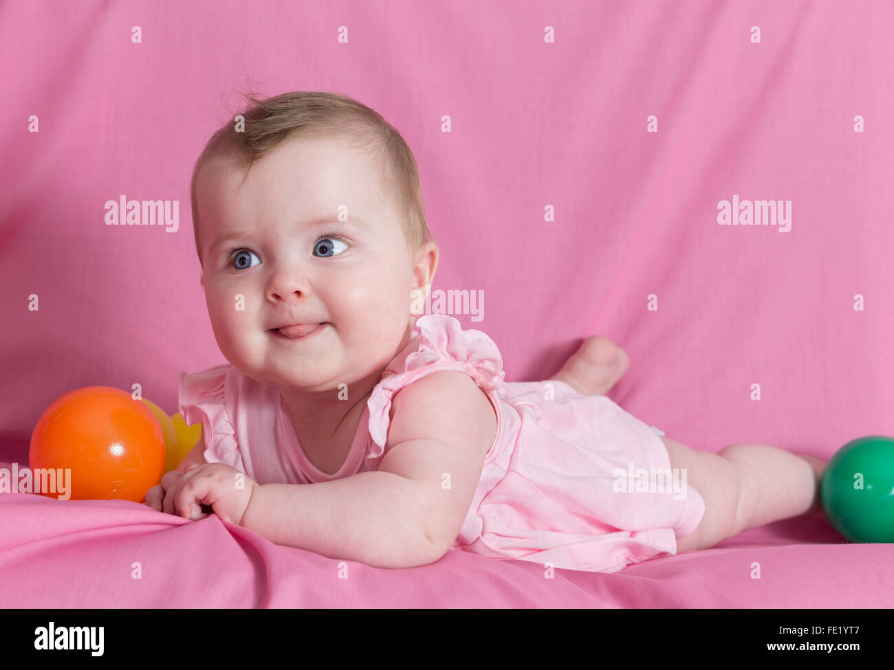 Adorable happy baby girl sur fond rose Banque D'Images