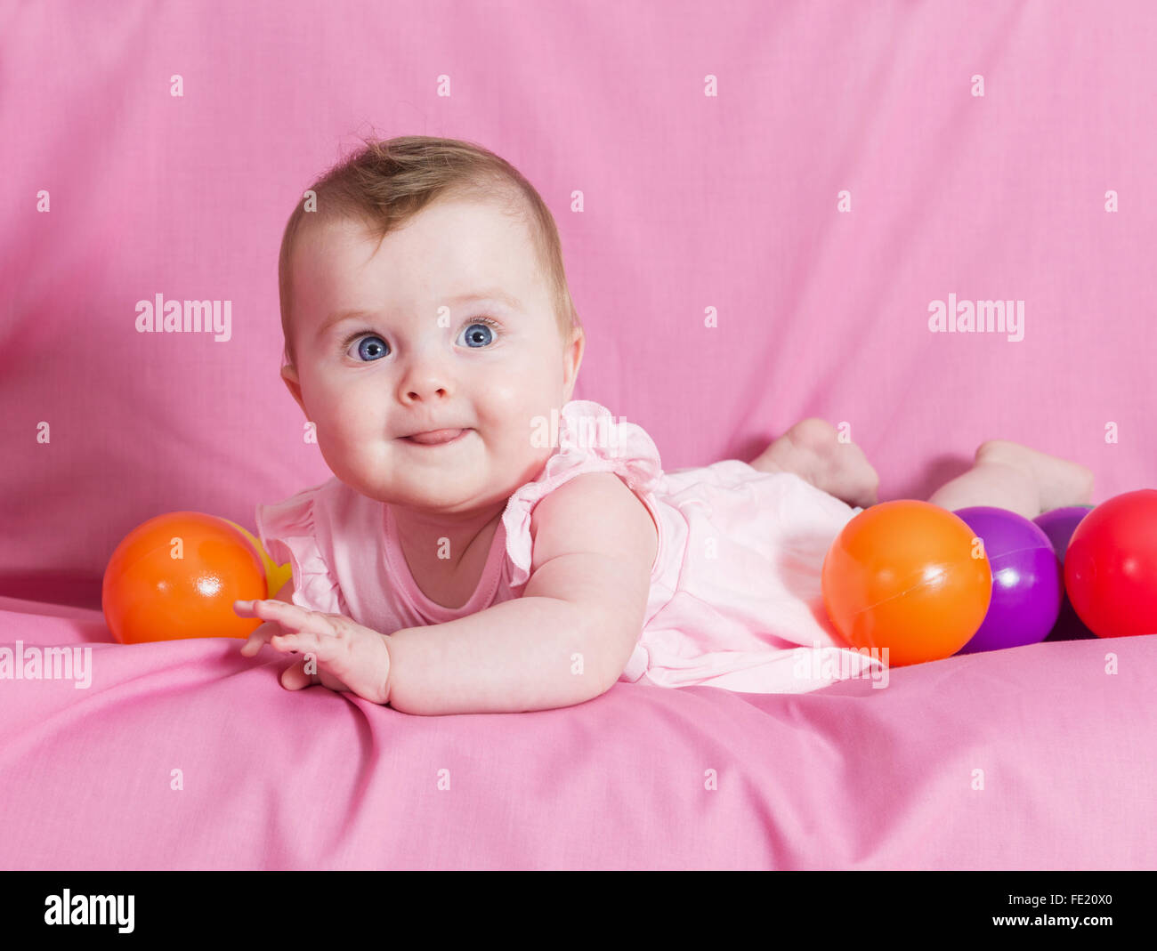 Adorable happy baby girl sur fond rose Banque D'Images