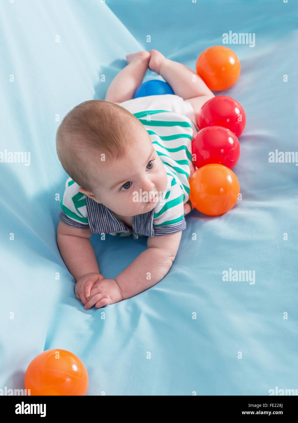 Adorable happy baby boy avec boules multicolores sur fond bleu Banque D'Images