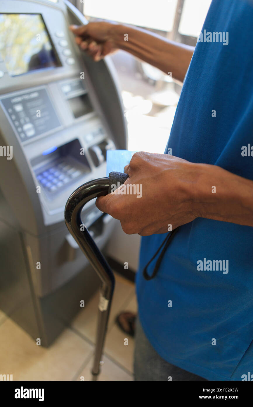 Homme avec un traumatisme crânien à l'aide d'un guichet automatique bancaire Banque D'Images