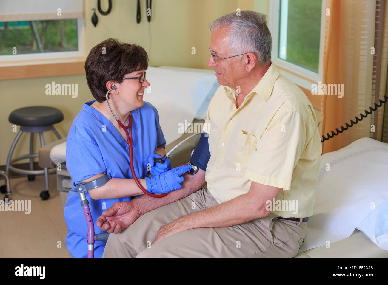 Nurse with Cerebral Palsy prenant une pression artérielle du patient dans une clinique Banque D'Images