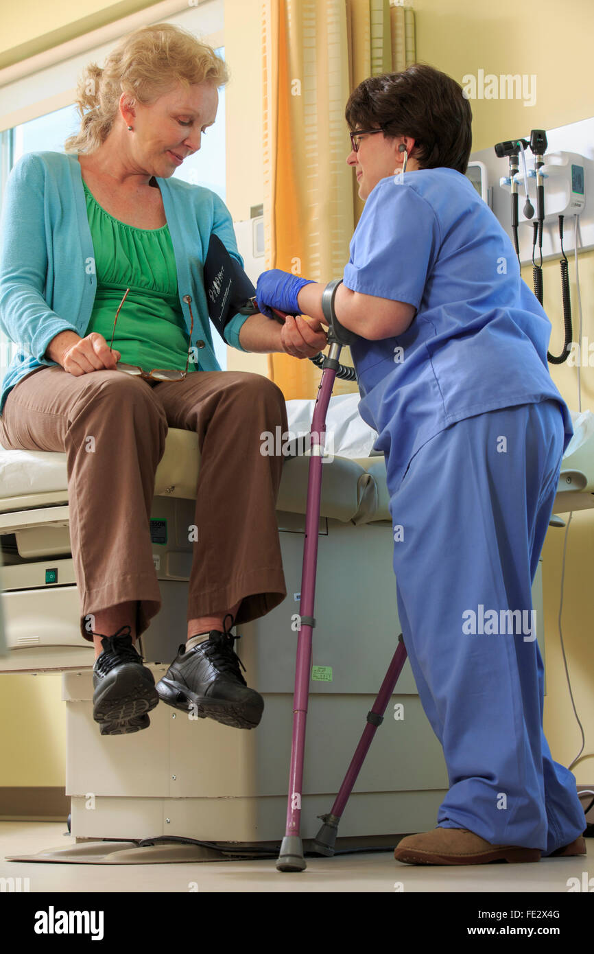 Nurse with Cerebral Palsy prenant une pression artérielle du patient dans une clinique Banque D'Images