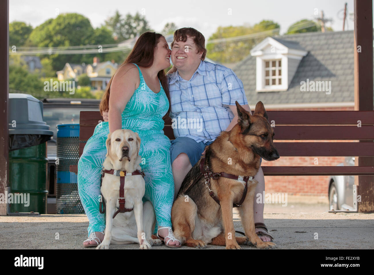 Jeune couple ayant une déficience visuelle et les chiens assis sur un banc et de dire un secret Banque D'Images