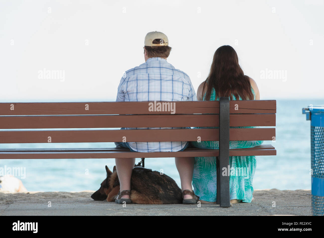 Couple d'aveugles assis sur un banc à la plage avec son chien Banque D'Images