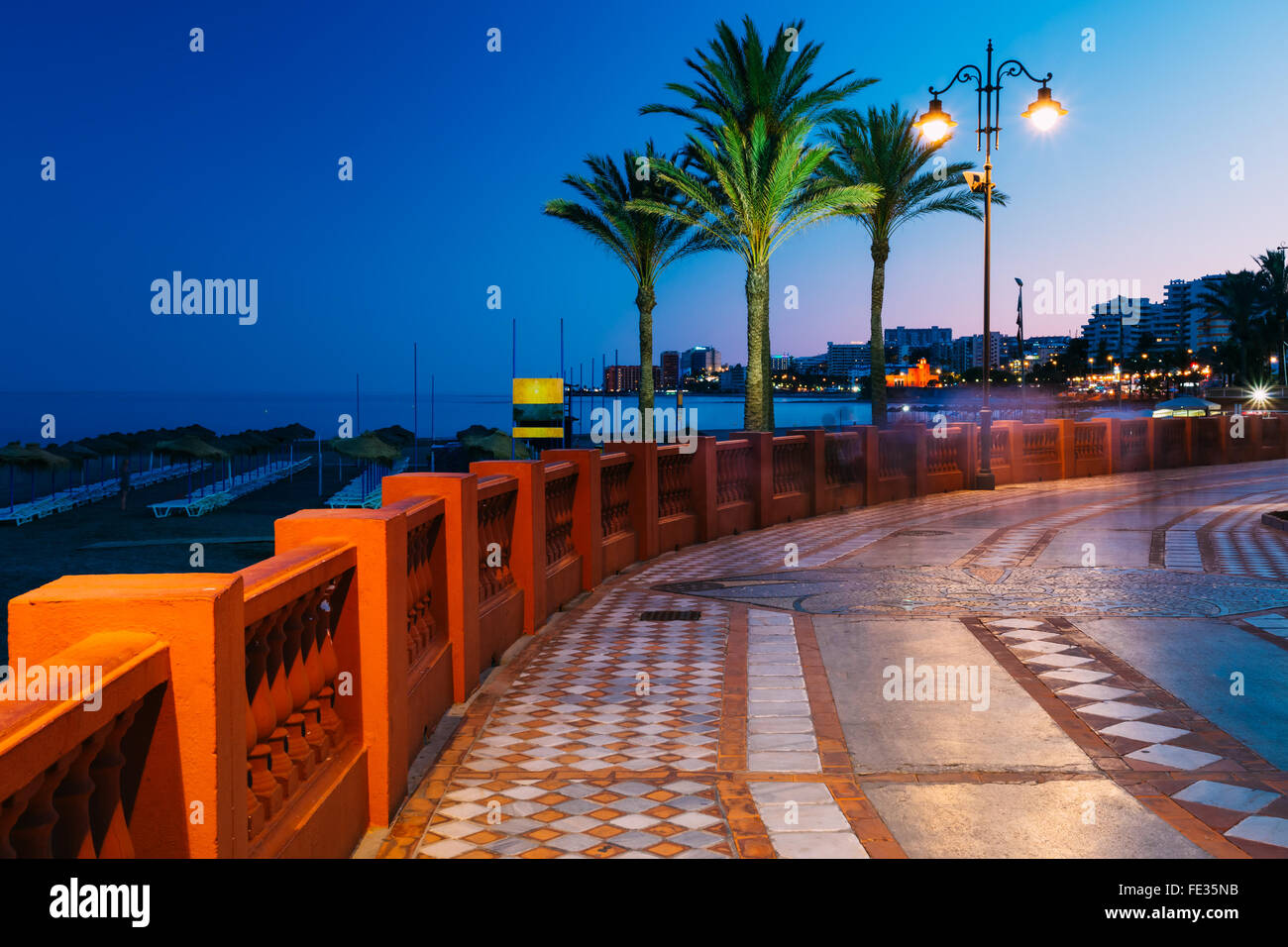 Superbe Vue de nuit sur la digue déserte dans Benalmadena, Andalousie ville. Promenade Sentier lumineux, palmiers, lampadaire, plage. Banque D'Images