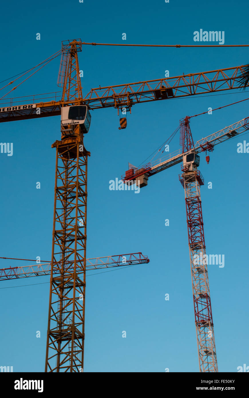 Low Angle View Of Cranes At Construction Site Against Cloudy Sky Banque D'Images