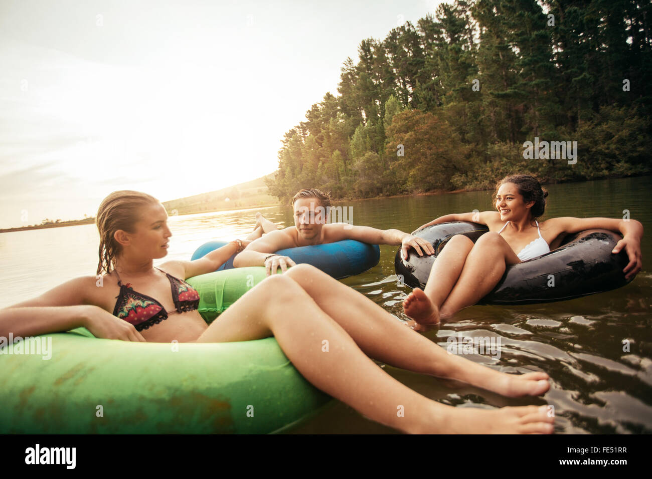 Portrait de jeunes amis flottant sur le lac avec anneaux gonflables. Les jeunes se détendre dans l'eau un jour d'été. Profitant de leur Banque D'Images