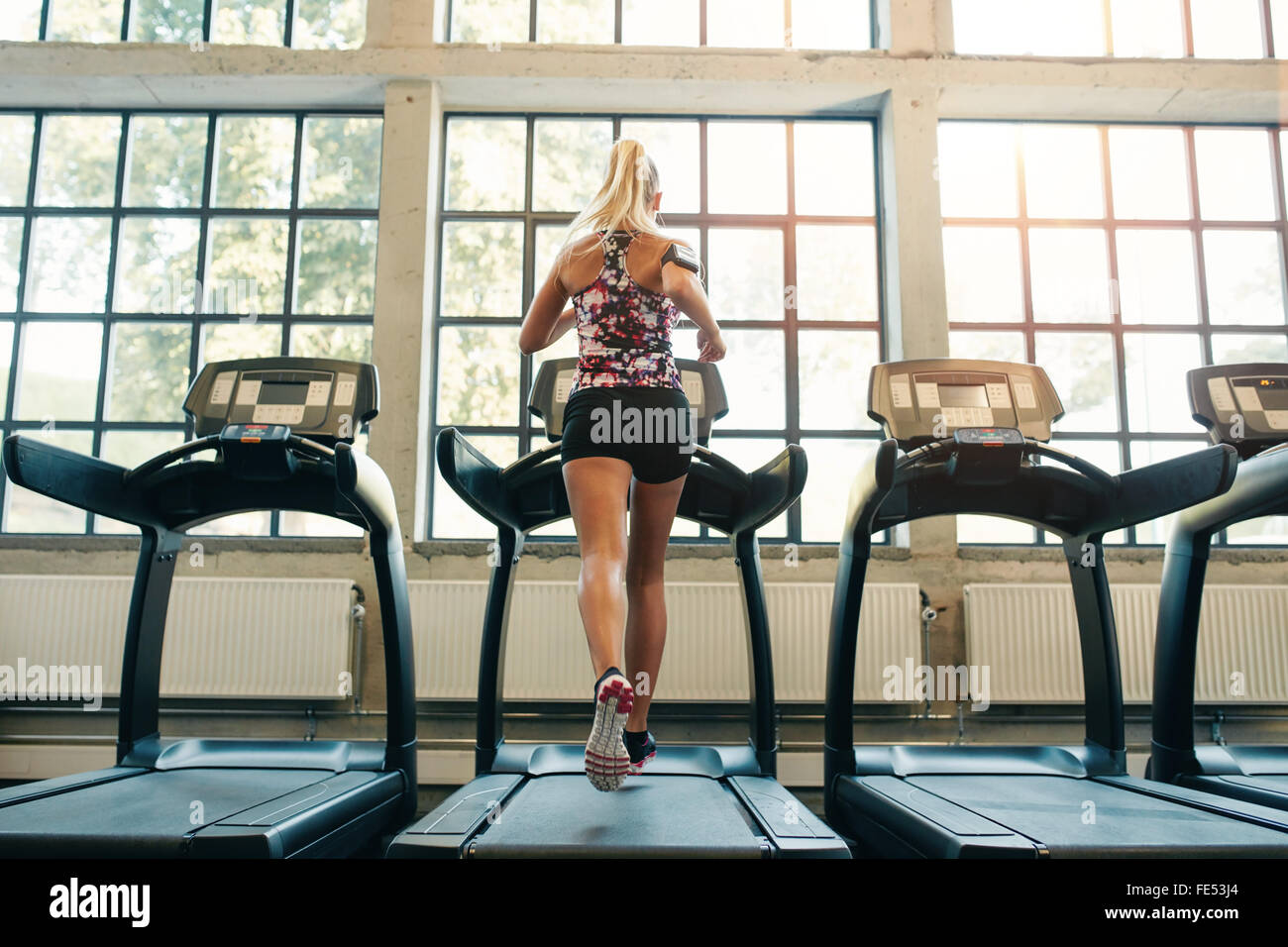 De l'horizontale le jogging sur tapis roulant à un club de santé. Femme à une salle de sport courir sur un tapis roulant. Banque D'Images