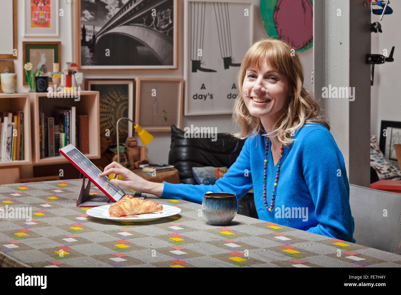 Femme à l'aide d'un iPad à une table du salon. Banque D'Images