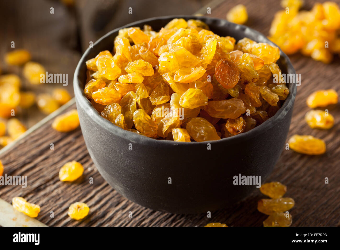 Séché bio Raisins secs dans un bol d'Or Banque D'Images