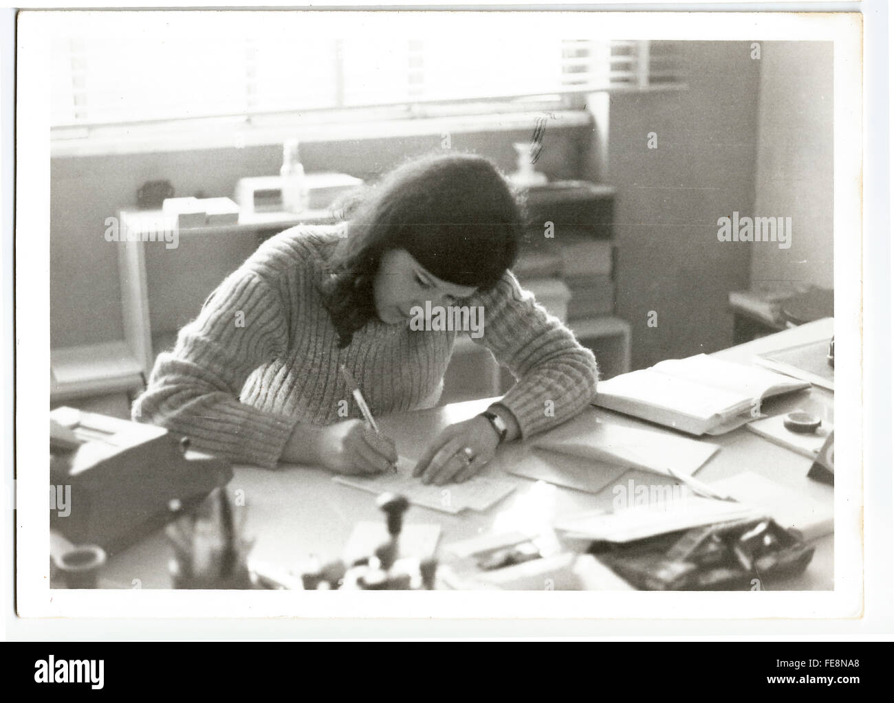 Secrétaire jeune femme tout en travaillant sur son bureau dans un environnement de bureau typique des années 70. Banque D'Images