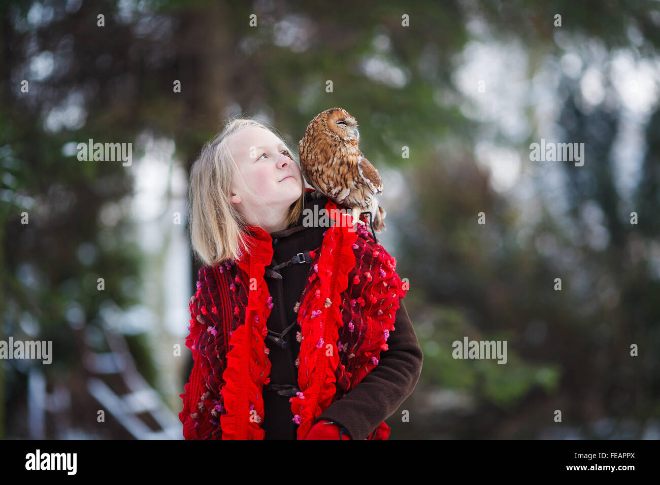 Jolie fille à l'écharpe rouge debout avec petit hibou dans un parc Banque D'Images