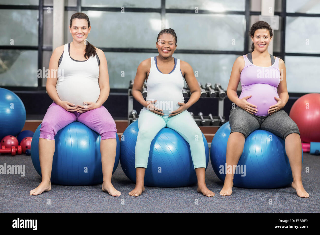 Les femmes enceintes joyeux assis sur l'exercice de boules et de toucher leurs ventres Banque D'Images