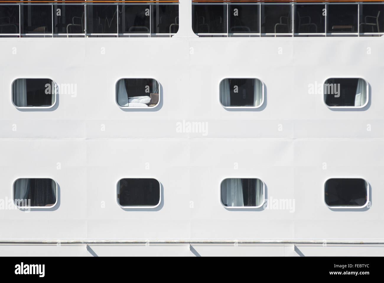 Close up of windows cabine en lignes formant un motif sur le livre blanc de la coque d'un bateau de croisière dans le port de Rostock, Allemagne Banque D'Images