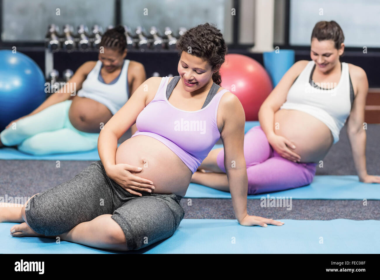 Les femmes enceintes faisant l'exercice sur mat Banque D'Images