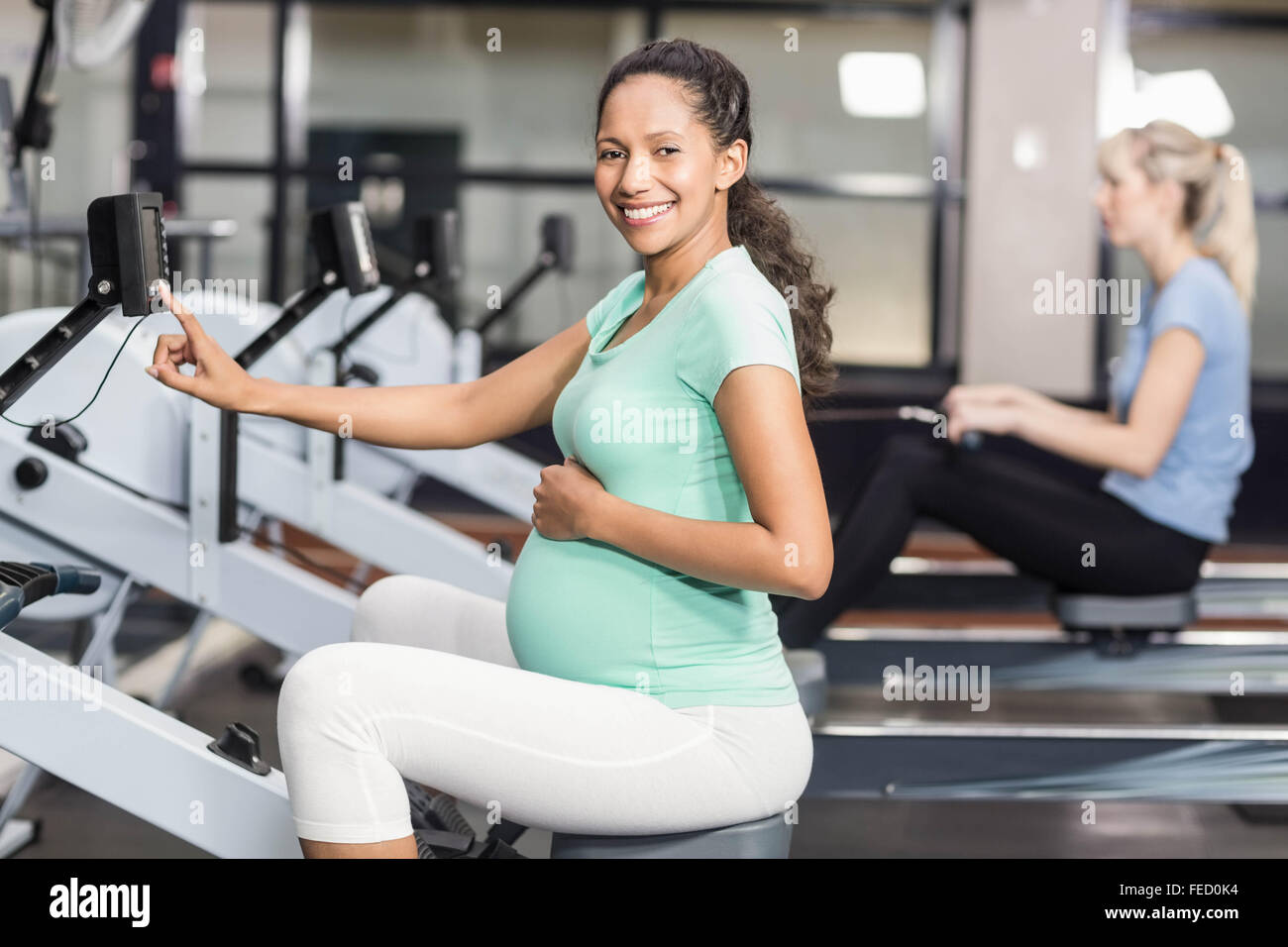 Femme enceinte l'exercice et à la recherche à l'appareil photo Banque D'Images