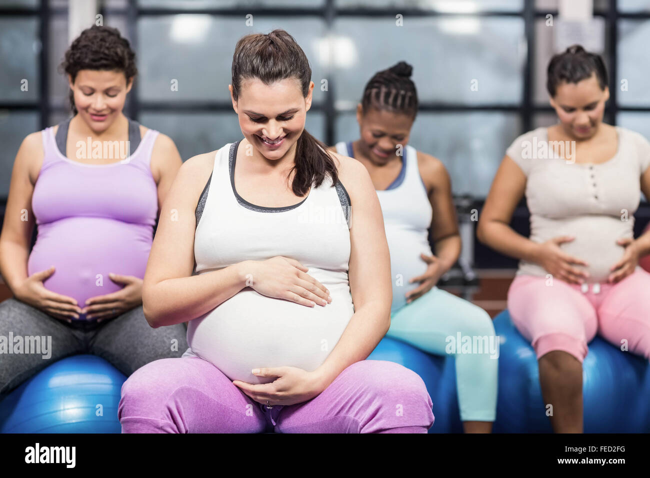 Les femmes enceintes assis sur l'exercice de boules et de toucher leurs ventres Banque D'Images