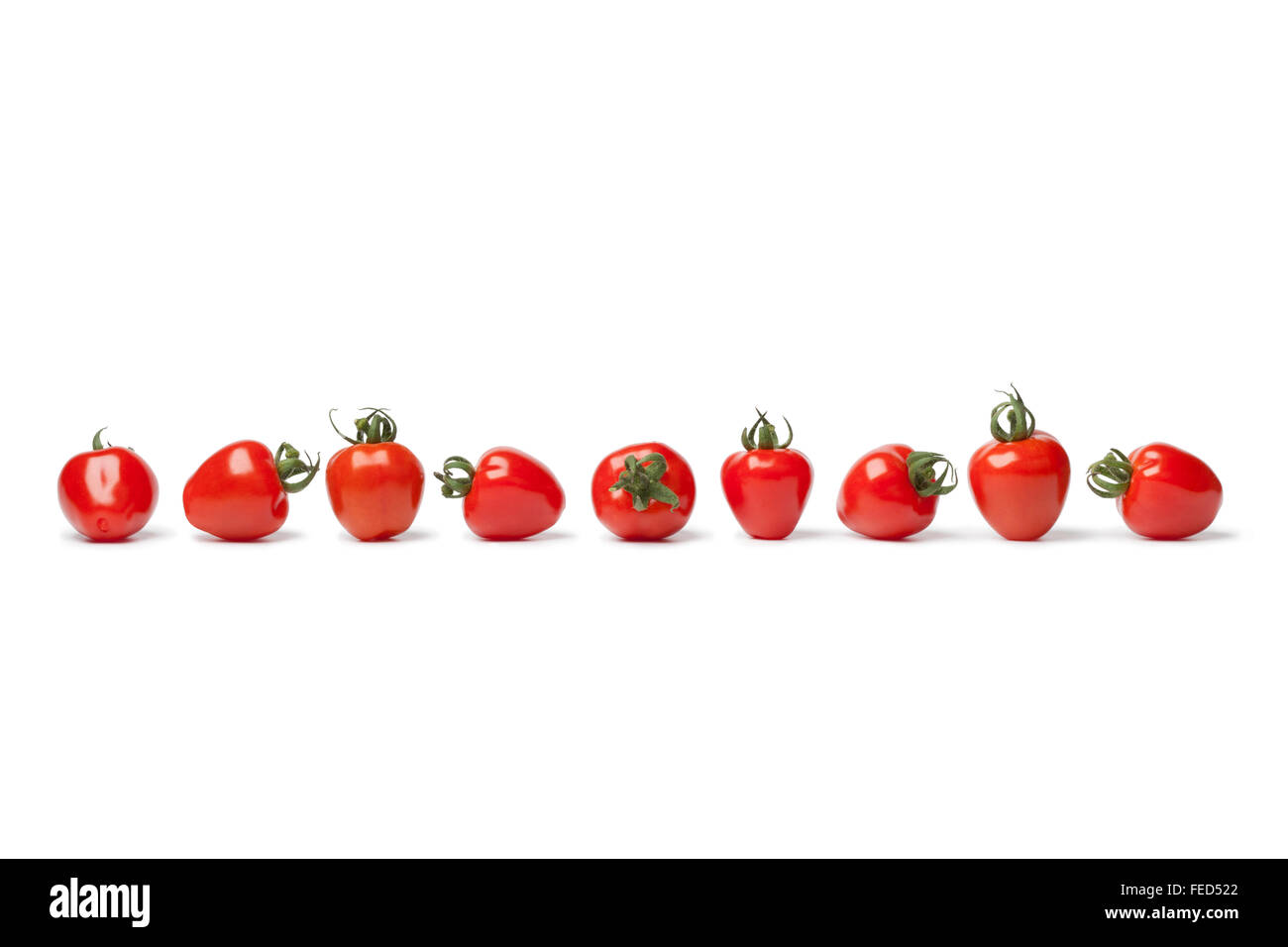 Tomates fraises fraîches dans une rangée sur fond blanc Banque D'Images