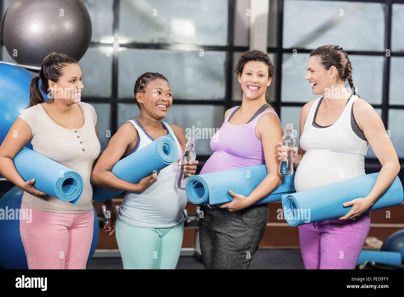 Smiling pregnant women holding tapis d'exercice et une bouteille d'eau Banque D'Images