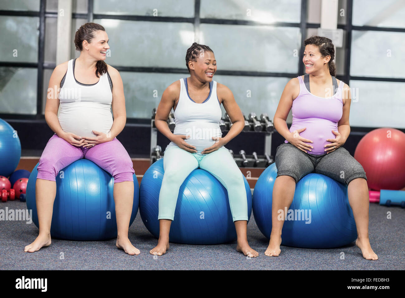 Les femmes enceintes joyeux assis sur l'exercice de boules et de toucher leurs ventres Banque D'Images