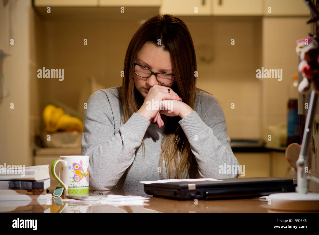Jeune femme de payer les factures en ligne tard dans la soirée après avoir terminé tous les travaux de sa maison, assis au bureau avec ordinateur, b Banque D'Images