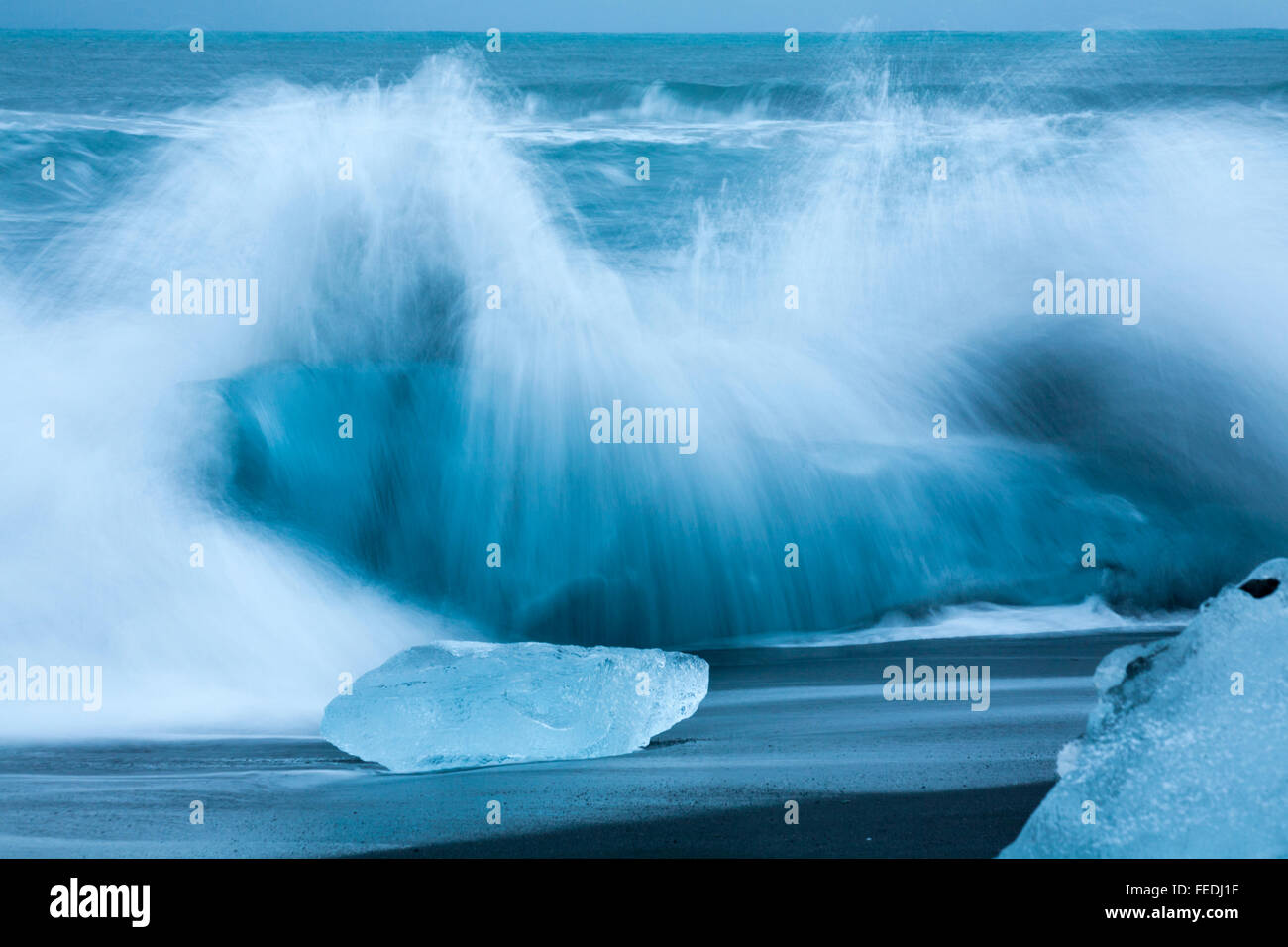 Une longue exposition de vagues déferlaient sur blocs de glace contrastant avec le sable noir à Jokulsarlon Glacial beach, plage du diamant, de l'Islande en Janvier Banque D'Images
