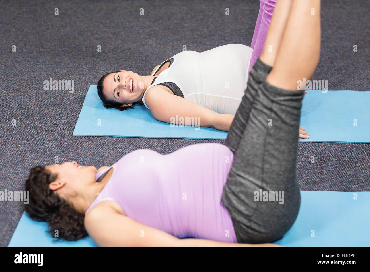 Les femmes enceintes faisant l'exercice sur mat Banque D'Images